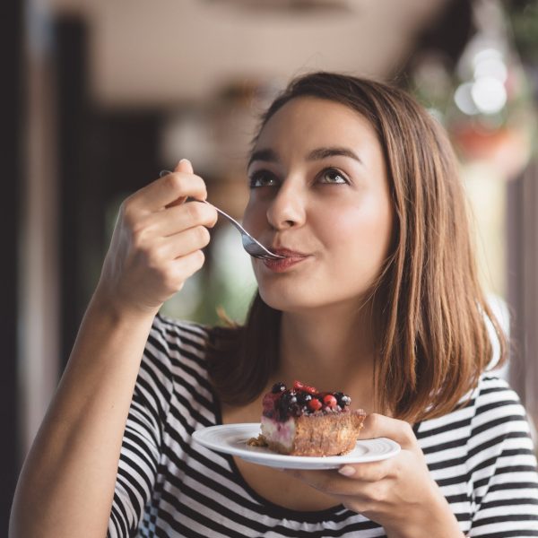 Young woman eating strawberry cheesecake